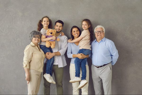 Photoshoot of family. Grandparents standing to the side, parents in the middle holding 2 young girls